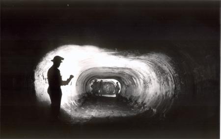 Miners appear in silhouette in a mine shaft