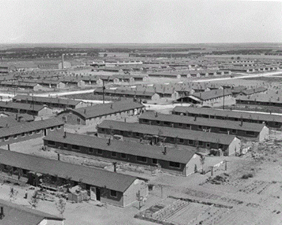Archival photo taken from a high point showing a town full of long buildings